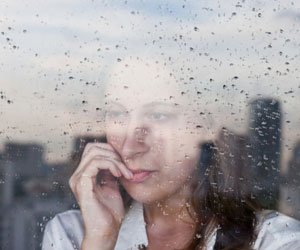 这是一个女人的照片在一个下雨的窗口。